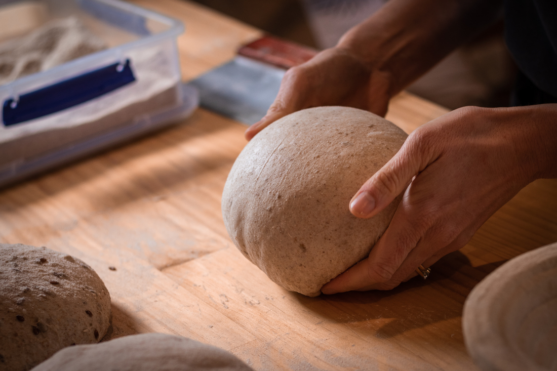 Hands shaping sourdough dough on a floured surface in a New Zealand home kitchen