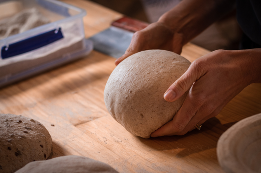 Hands shaping sourdough dough on a floured surface in a New Zealand home kitchen
